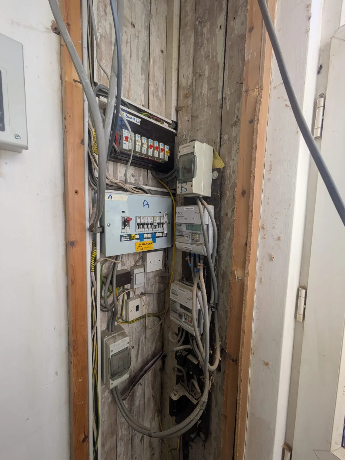 Old consumer unit with tangled wiring before upgrade